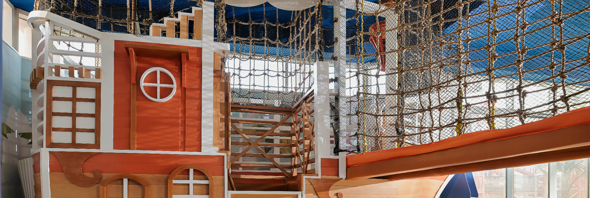 Large wooden indoor play structure designed like a colourful pirate ship for children